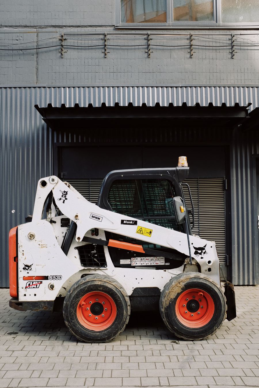 PLACEHOLDER - compact loader outside a warehouse