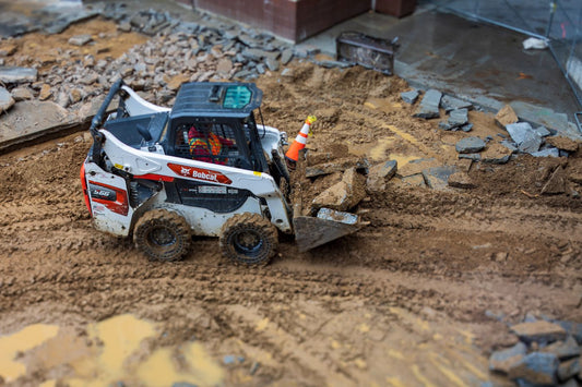 PLACEHOLDER - skid steer loader moving rock on a muddy site